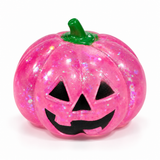 Pink translucent glitter Halloween pumpkin squishy with a jack-o'-lantern face
