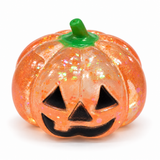 Pale orange translucent glitter Halloween pumpkin squishy with a jack-o'-lantern face