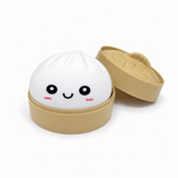 White smiling dumpling squishy in a tan steamer-style container with lid
