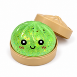 Light green glitter dumpling squishy in a tan steamer-style container with lid